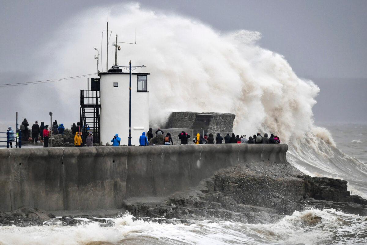 People watch waves and rough seas pound against the harbor wall at Porthcawl in Wales, as Storm Dennis sweeps across the country, on Feb. 15, 2020. (Ben Birchall/PA via AP)