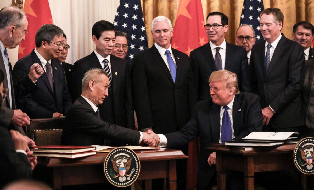 Chinese Vice Premier Liu He (L) and U.S. President Donald Trump during the signing of phase one of a trade deal, surrounded by officials, in the East Room of the White House in Washington on Jan. 15, 2020. (Charlotte Cuthbertson/The Epoch Times)