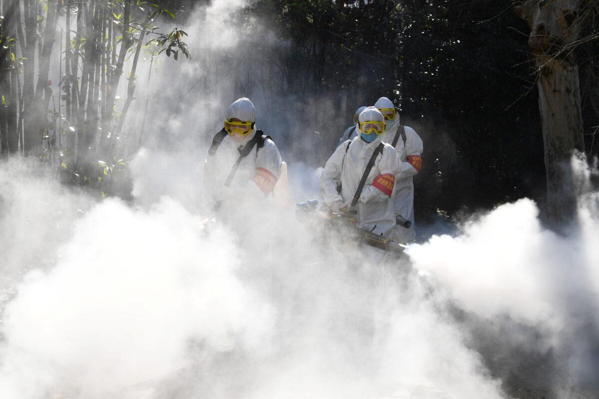 Sanitation workers disinfect a residential compound, as the country is hit by an outbreak of the novel coronavirus, in Bozhou in Anhui Province, China on Feb. 18, 2020. (China Daily via Reuters)