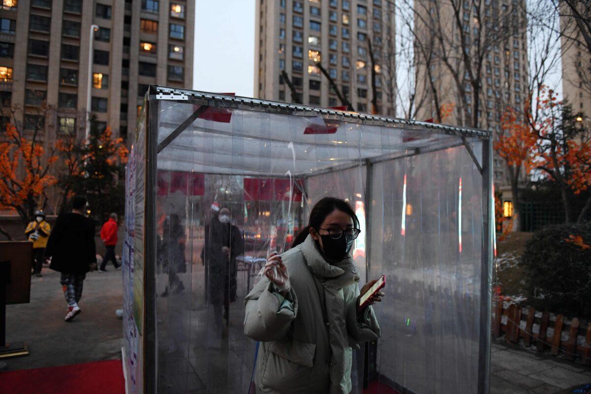 A resident emerges from a disinfection channel set up as a protective measure against the COVID-19 coronavirus at the entrance to her compound in Tongzhou, east of Beijing, on Feb. 18, 2020. (Greg Baker/AFP via Getty Images)
