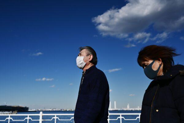 People wearing face masks walk by the coast in Yokohama, Japan on Feb. 18, 2020. (Charly Triballeau/AFP via Getty Images)