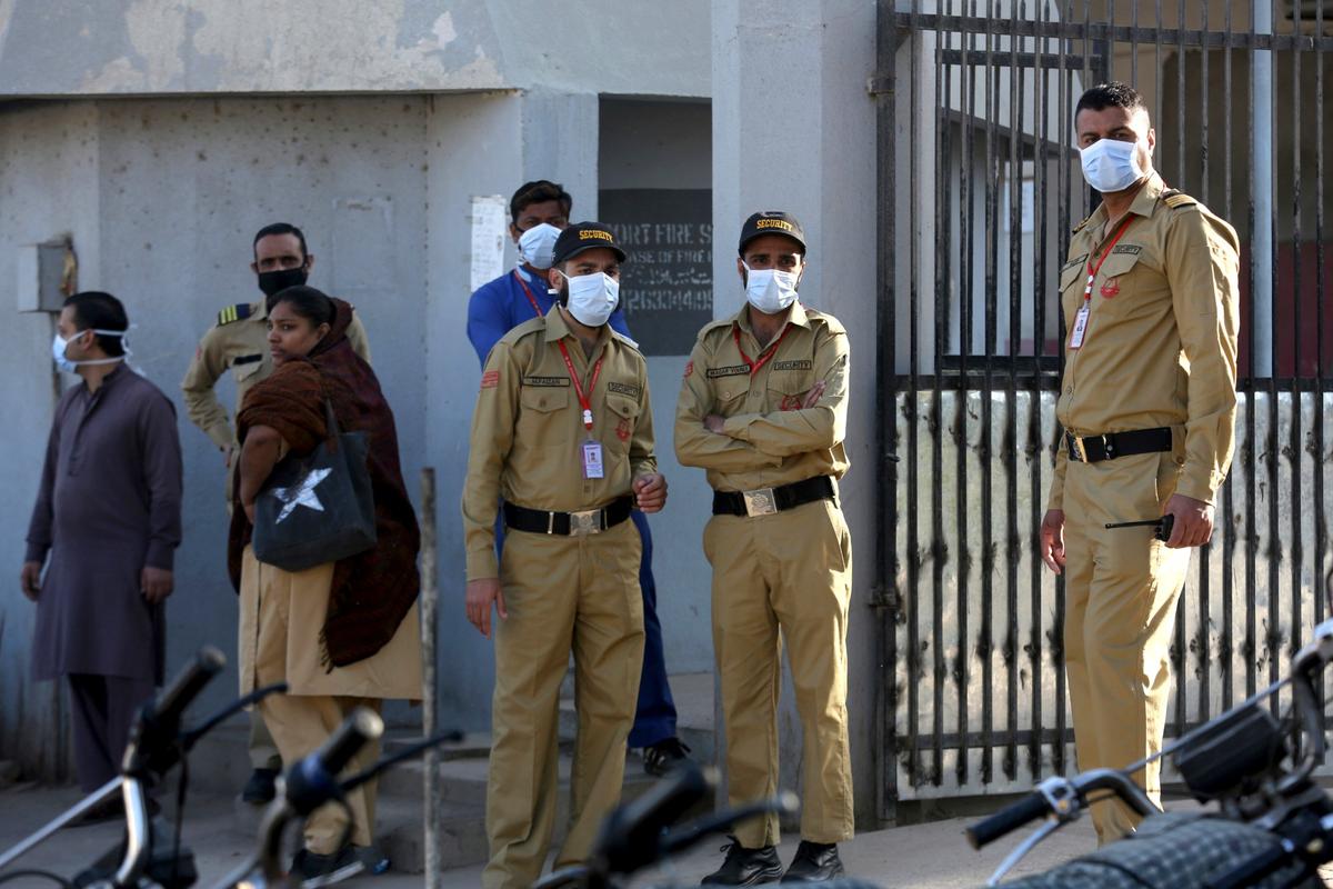 Private guards wear masks while standing outside a hospital, where victims of toxic gas leak are treated in Kamari neighborhood of Karachi, Pakistan, on Feb. 17, 2020. (Fareed Khan/AP Photo)