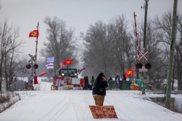A man with a sign stands near the site of a rail stoppage on Tyendinaga Mohawk Territory, as part of a protest against British Columbia's Coastal GasLink pipeline, in Tyendinaga, Ont., on Feb. 15, 2020. (Carlos Osorio/File Photo via Reuters)
