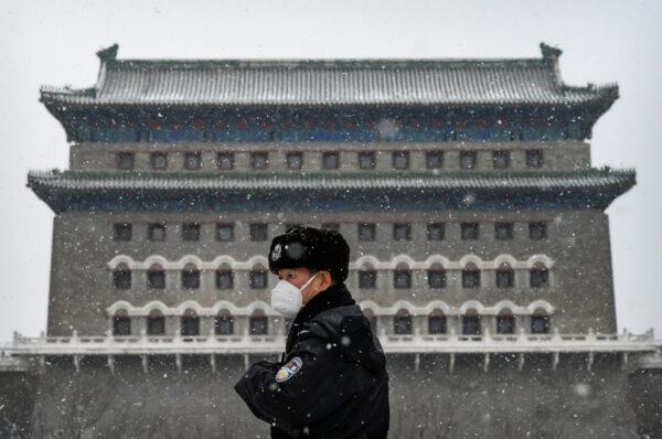 A Chinese police officer wears a protective mask as he stands guard outside the Qianmen Gate during a snowfall in an empty and shuttered commercial street in Beijing, China, on Feb. 5, 2020. (Kevin Frayer/Getty Images)