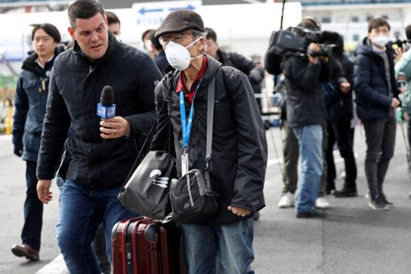A member of the media approaches a passenger as he walks out from the cruise ship Diamond Princess at Daikoku Pier Cruise Terminal in Yokohama, Japan, on Feb. 19, 2020. (Athit Perawongmetha/Reuters)