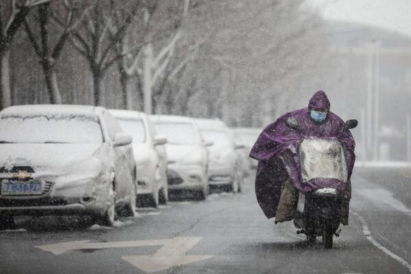 A man wears a protective mask as he rides a bike as snow falls in Wuhan, Hubei, China, on Feb. 15, 2020. (Getty Images)