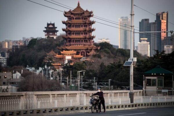 A woman is walking with a bicycle in Wuhan, China on Feb. 17, 2020. (STR/AFP via Getty Images)