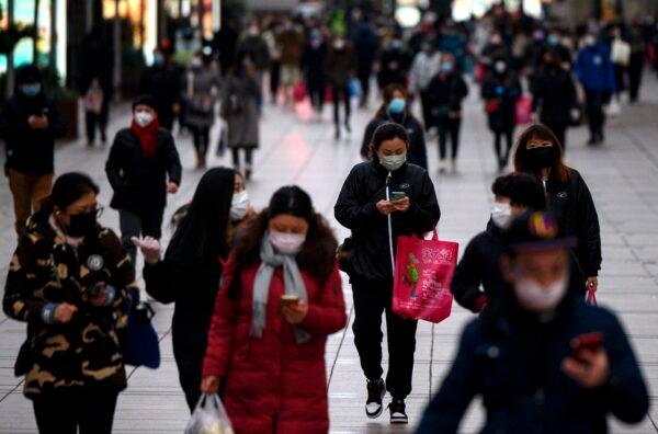 People wearing protective facemasks walk along a street in Shanghai, China, on Feb. 19, 2020. (Noel Celis/AFP via Getty Images)
