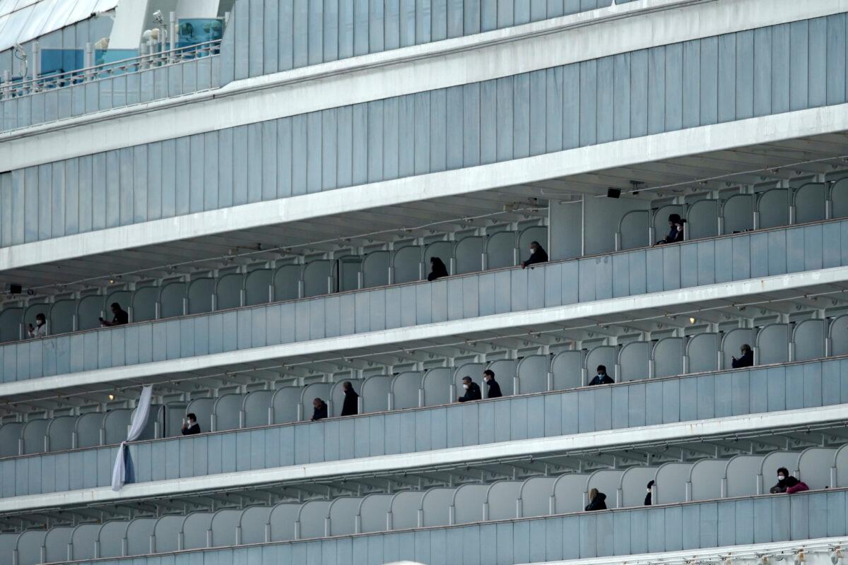 Some passengers look out from the balcony of the quarantined Diamond Princess cruise ship at a port in Yokohama, near Tokyo on Feb. 19, 2020. (Eugene Hoshiko/AP Photo)