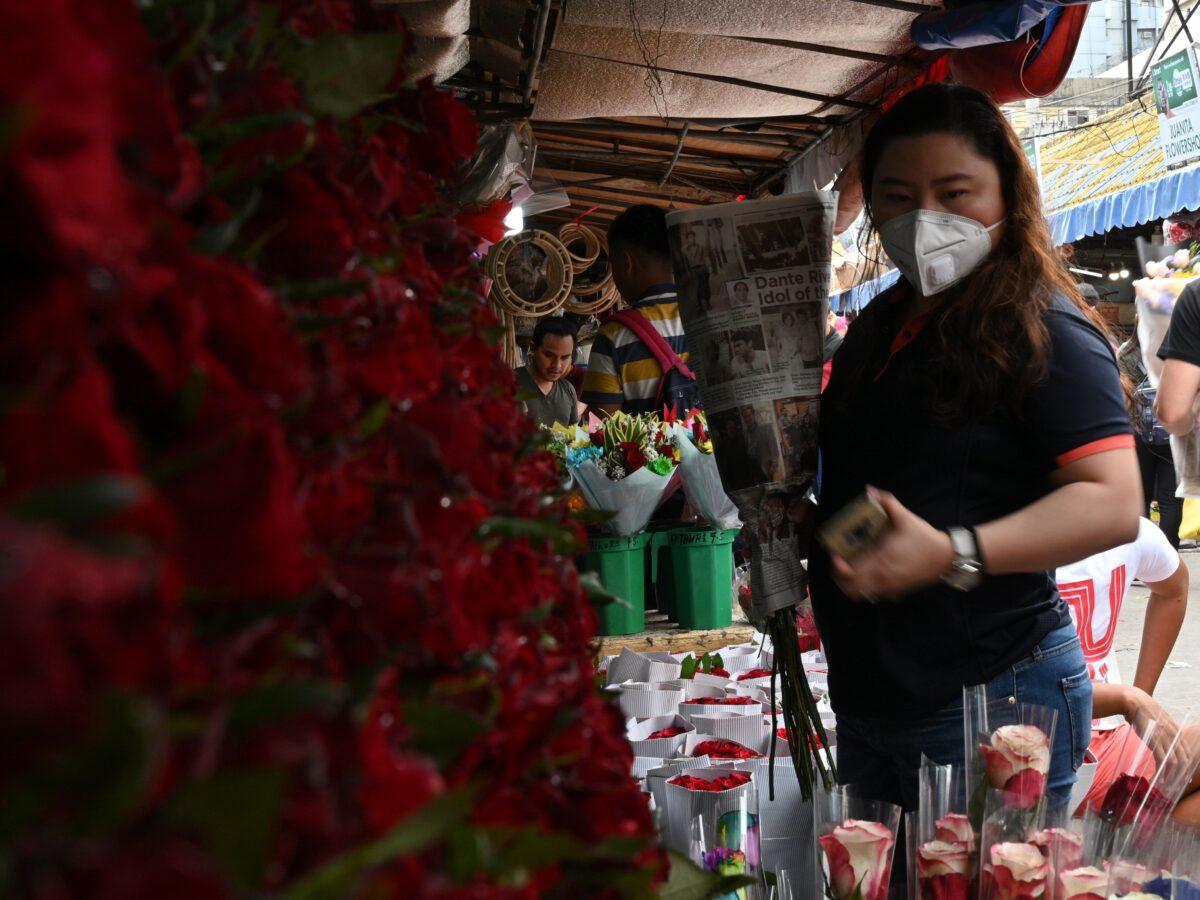 A woman wearing a protective facemask buys flowers on Valentine's day at a flower market in Manila in the Philippines on Feb. 14, 2020. (Ted Aljibe/AFP via Getty Images