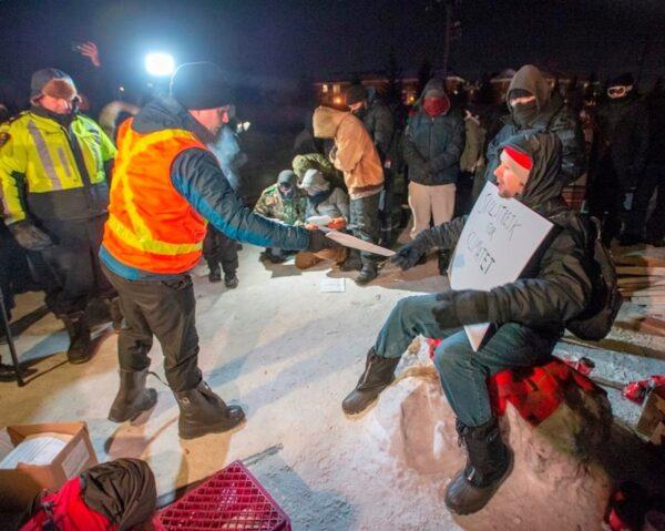 Police serve an injunction to protesters at a rail blockade in St. Lambert, south of Montreal, on Feb. 20, 2020. (Ryan Remiorz/The Canadian Press)