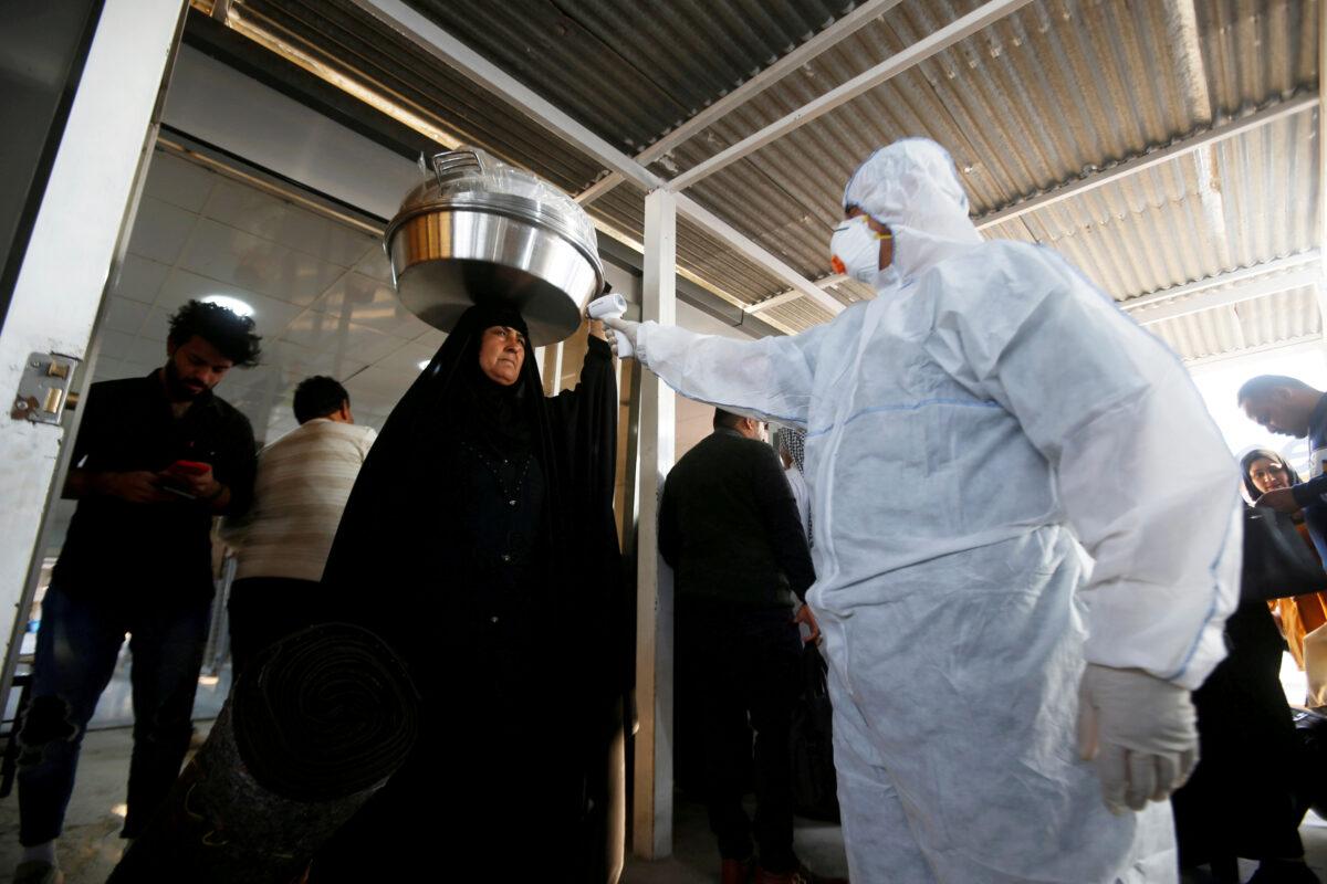 An Iraqi medical staff member checks a passenger's temperature, amid the new coronavirus outbreak, upon her arrival to Shalamcha Border Crossing between Iraq and Iran, on Feb. 20, 2020. (Essam al-Sudani/Reuters)