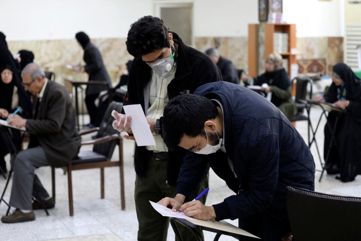 Voters with face masks fill out their ballots in the parliamentary elections at a polling station in Tehran, Iran, on Feb. 21, 2020. (Vahid Salemi/AP Photo)