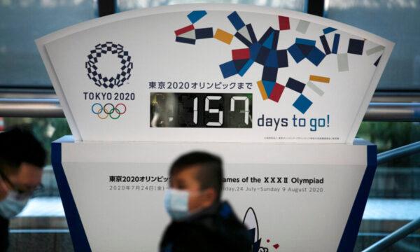 People wearing masks sit in front of a countdown clock for the Tokyo 2020 Olympics in Tokyo, on Feb. 18, 2020. (Jae C. Hong/AP Photo, File)