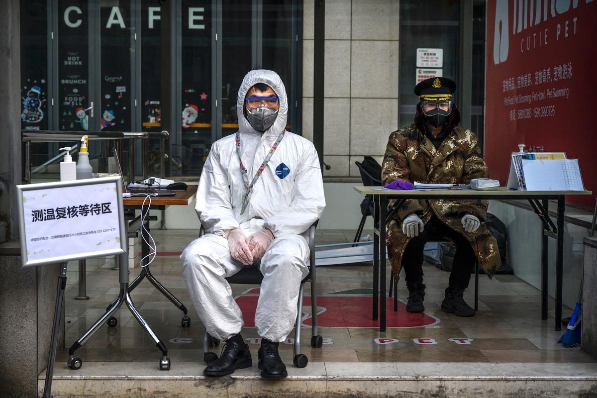 A Chinese guard wears a protective mask and suit as he waits to check temperatures and register people entering a building in a commercial area in Beijing, China, on Feb. 21, 2020. (Kevin Frayer/Getty Images)