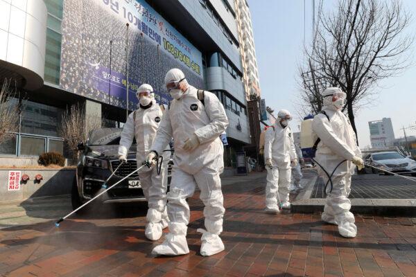 Workers wearing protective gear spray disinfectant against the new coronavirus in front of a church in Daegu, South Korea, on Feb. 20, 2020. (Kim Jun-beom/Yonhap via AP)