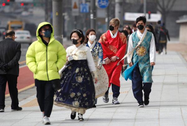 Visitors wearing face masks walk near the Gwanghwamun, the main gate of the 14th-century Gyeongbok Palace, and one of South Korea's well-known landmarks, in Seoul on Feb. 22, 2020. (Lee Jin-man/AP Photo)