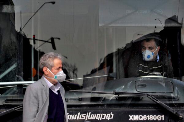 A public bus driver and a pedestrian wear masks to help guard against the coronavirus in downtown Tehran, Iran, on Feb. 23, 2020. (Ebrahim Noroozi/AP Photo)