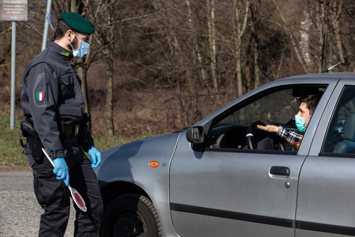 An Italian Guardia di Finanza (Custom Police) officer, wearing a respiratory mask, talks to a driver at a roadblock in Casalpusterlengo, south-west Milan, Italy, on Feb. 24, 2020. (Emanuele Cremaschi/Getty Images)