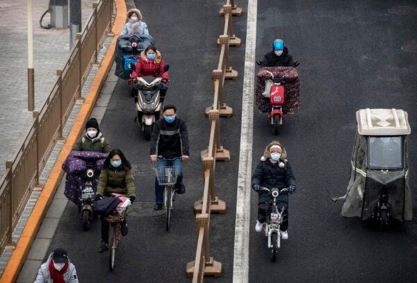 Chinese commuters, all wearing protective masks, ride bikes and scooters as they cross an intersection in rush hour in Beijing on Feb. 24, 2020. (Kevin Frayer/Getty Images)