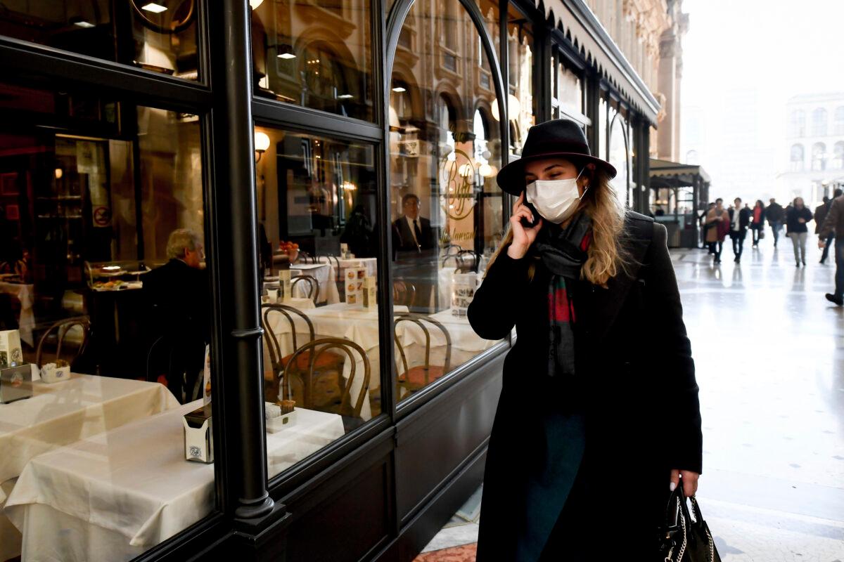 A woman wearing a sanitary mask talks on the phone as she walks in the Vittorio Emanuele Gallery shopping arcade, in downtown Milan, Italy on Feb. 24, 2020. (Claudio Furlan/Lapresse via AP)