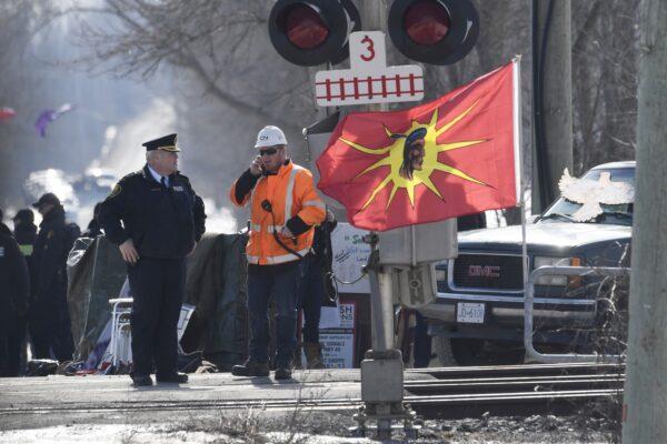 An Ontario Provincial Police officer talks to a CN Rail employee after arrests were made at a rail blockade in Tyendinaga Mohawk Territory near Belleville, Ont., on Feb. 24, 2020.  (The Canadian Press/Adrian Wyld)