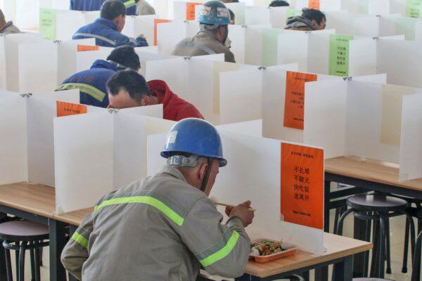 Workers are having lunch at a dining hall using boards to separate people to prevent the spread of the COVID-19 coronavirus in Yantai in Shandong, China, on Feb. 10, 2020. (STR/AFP via Getty Images)