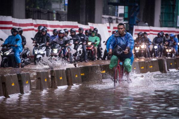 A cyclist rides alongside motorcyclists along a flooded street in Jakarta, Indonesia, on Feb. 25, 2020. (Antara Foto/Aprillio Akbar/via Reuters)