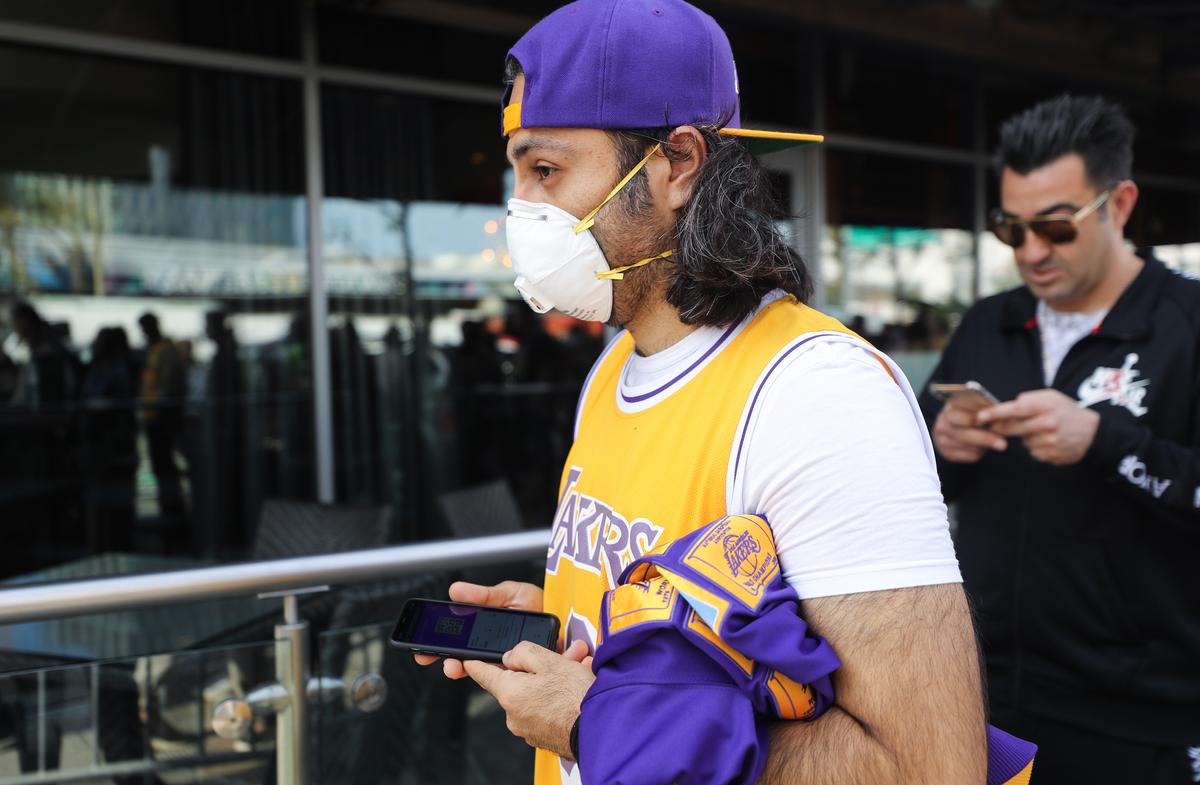 A fan wears a protective mask as people wait in line to attend the ‘Celebration of Life for Kobe and Gianna Bryant’ memorial service at Staples Center in Los Angeles, California, on Feb. 24, 2020. (Mario Tama/Getty Images)