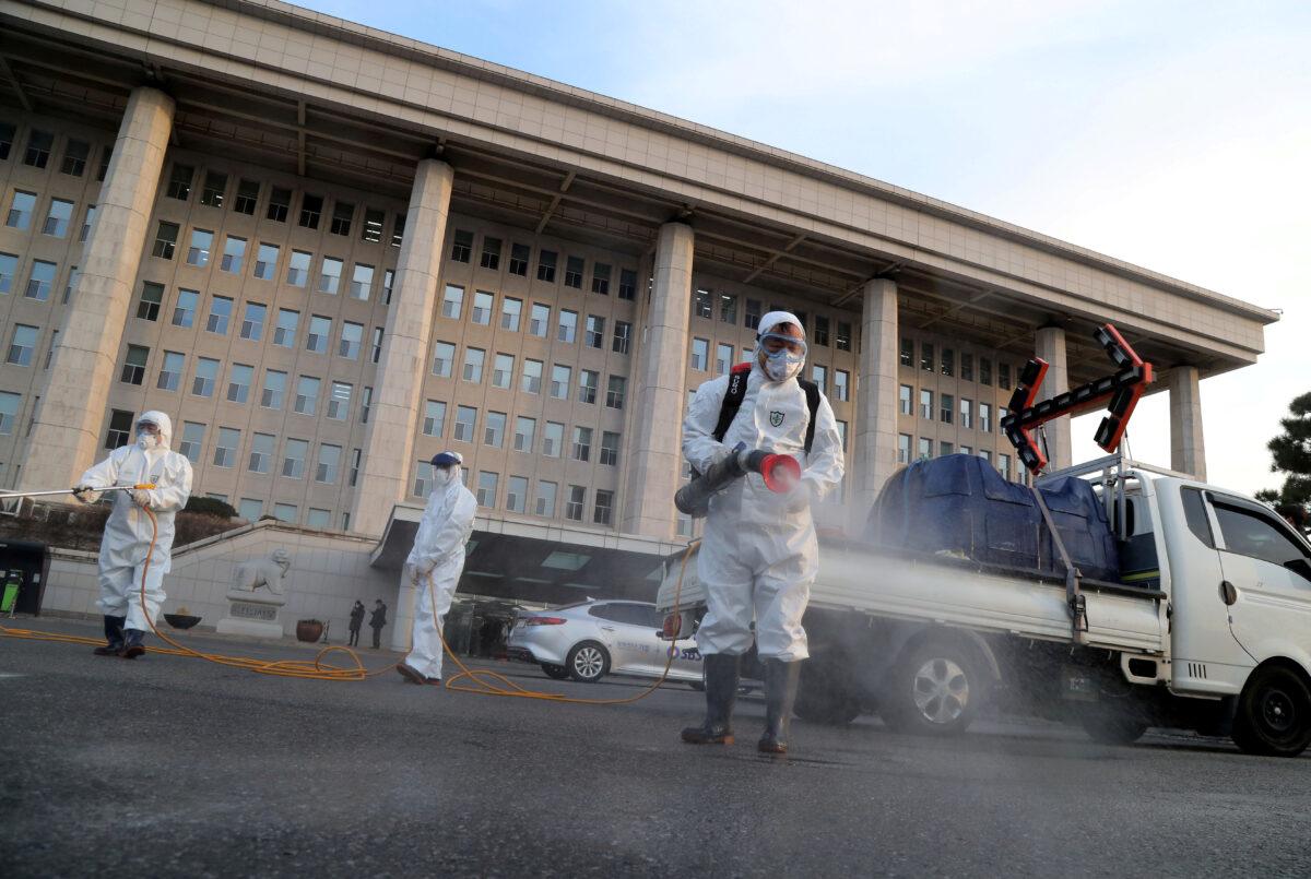 Employees from a disinfection service company sanitize outside the National Assembly in Seoul on Feb. 24, 2020. (Yonhap via Reuters)