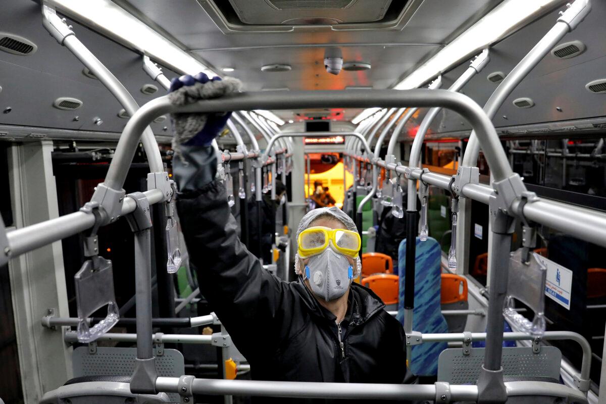 A worker disinfects a public bus against coronavirus in Tehran, Iran, in the early morning of Feb. 26, 2020. (Ebrahim Noroozi/AP Photo)