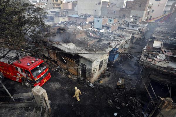 A firefighter walks past damaged shops at a tire market after they were set on fire by a mob in a riot-affected area in New Delhi, India, on Feb. 26, 2020. (Adnan Abidi/Reuters)