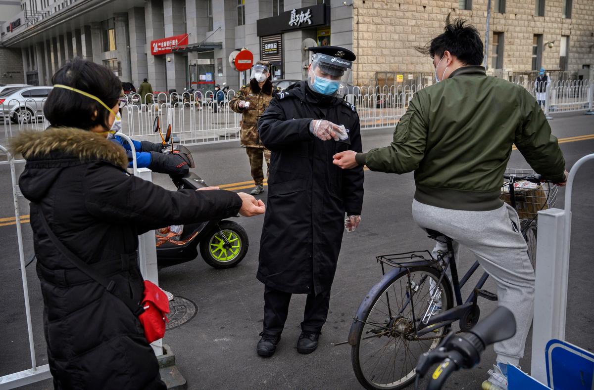 A Chinese security guard wears a protective mask as he checks the temperature of people entering a residential building in Beijing, China, on Feb. 26, 2020. (Kevin Frayer/Getty Images)