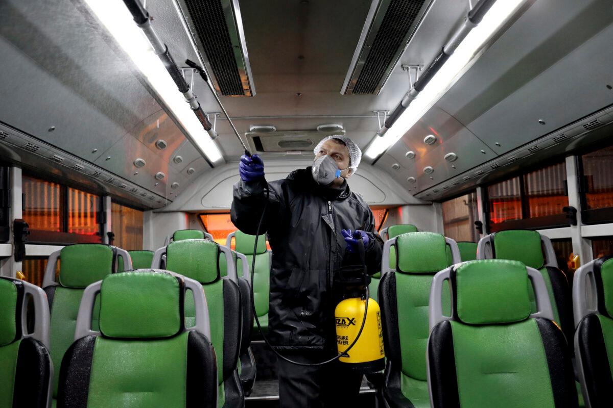 A worker disinfects a public bus against coronavirus in Tehran, Iran, on Feb. 26, 2020. (Ebrahim Noroozi/AP Photo)