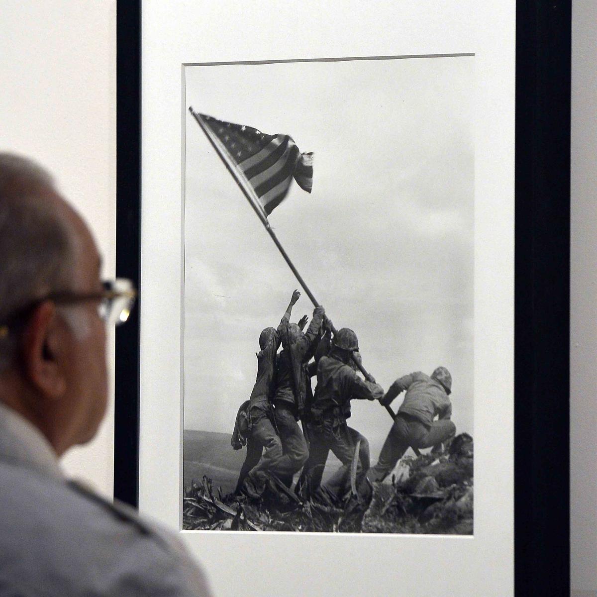 A visitor looks at Joe Rosenthal's "Raising the Flag on Iwo Jima" 1945 during the "Life. I grandi fotografi" (Life. The great photographers) exhibition at the auditorium on April 30, 2013, in Rome. (GABRIEL BOUYS/AFP via Getty Images)
