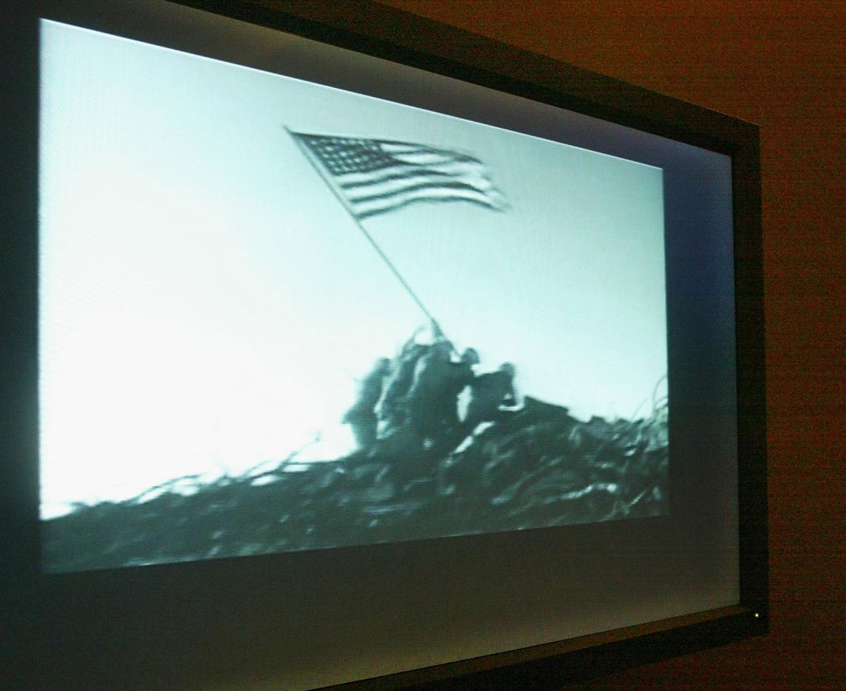 Footage of the scene of U.S. Marines raising a U.S. flag at Iwo Jima during World War II is played at the newly opened "From the Home Front and the Front Lines" exhibition at the Library of Congress May 24, 2004 in Washington. (Alex Wong/Getty Images)