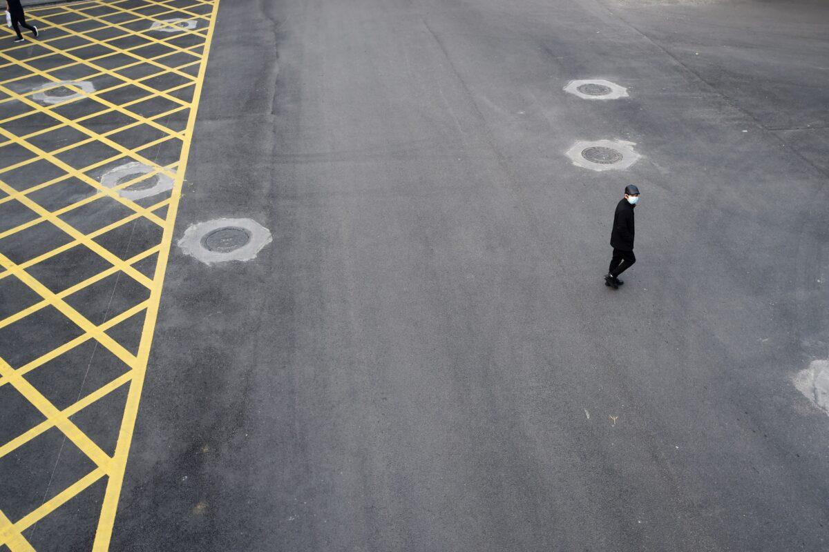 A man wearing a face mask crosses a road in Wuhan, the epicentre of the novel coronavirus outbreak, Hubei Province, China on Feb. 24, 2020. (Stringer/Reuters)