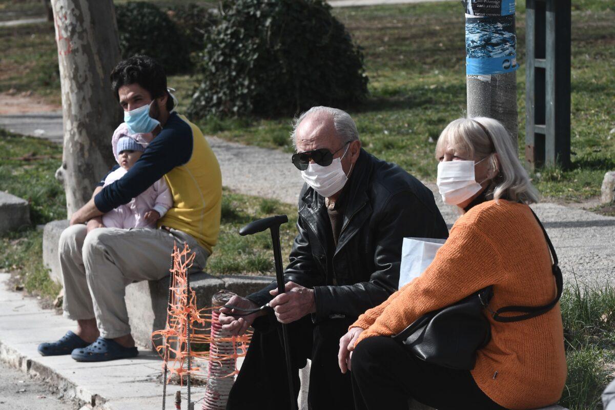 People with face masks sit outside of the hospital of Ahepa in Thessaloniki, Greece, on Feb. 26, 2020, the same day the country reported its first case of the new coronavirus. (Sakis Mitrolidis/AFP via Getty Images)