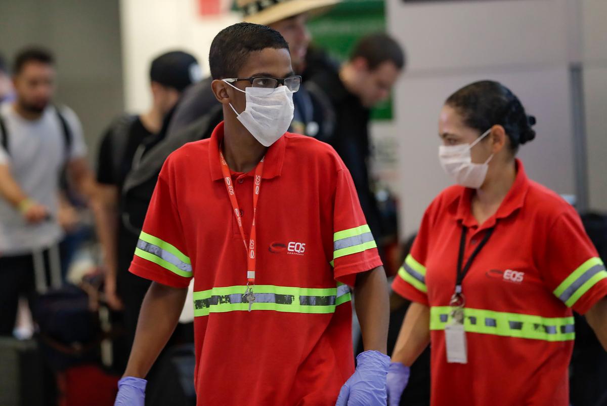 Airport employees wear masks as a precaution against the spread of the new coronavirus COVID-19 as they work at the Sao Paulo International Airport in Sao Paulo, Brazil, on Feb. 26, 2020. (Andre Penner/AP Photo)