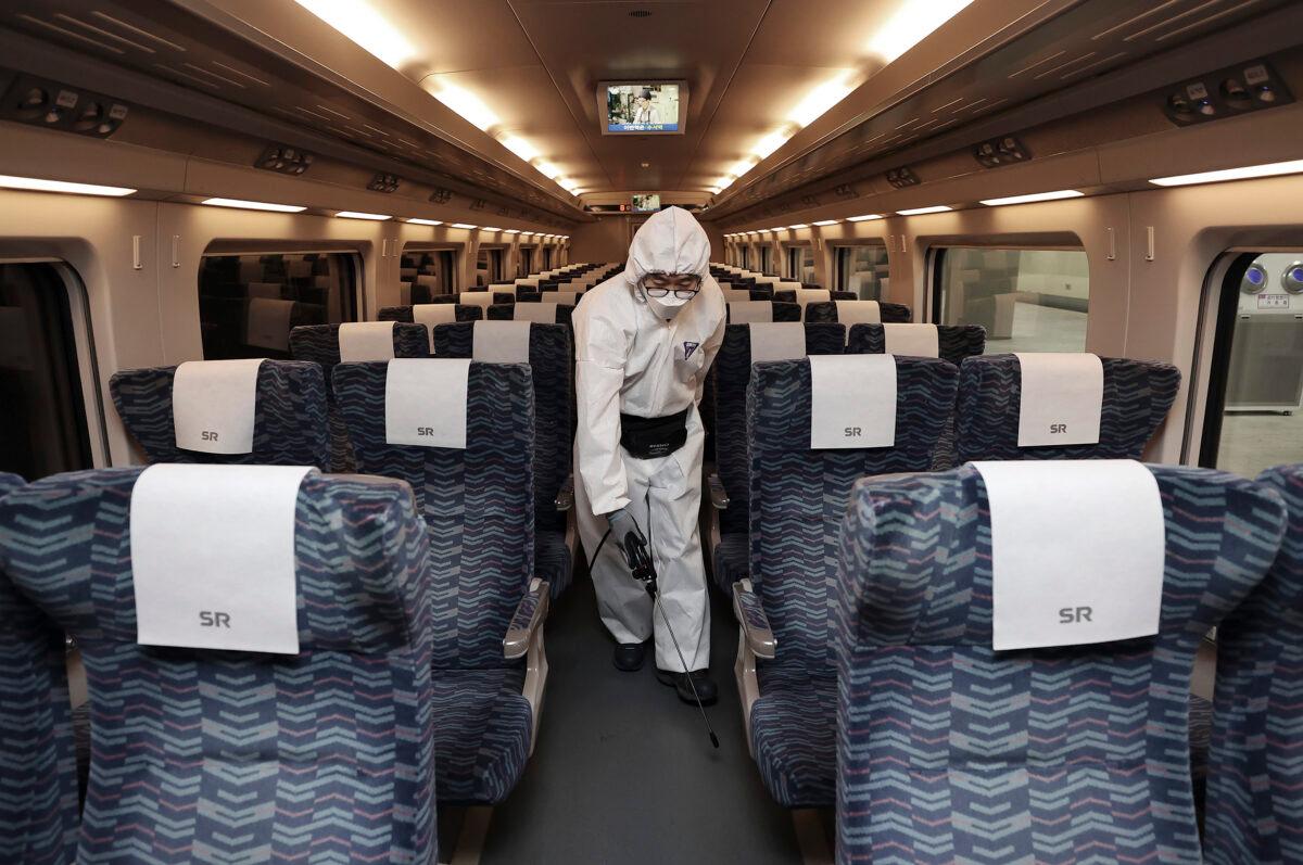 A worker wearing protective gears sprays disinfectant as a precaution on a train against the new coronavirus at Suseo Railway Station in Seoul, South Korea on Feb. 25, 2020. (Lee Ji-eun/Yonhap via AP)