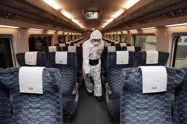 A worker wearing protective gears sprays disinfectant as a precaution on a train against the new coronavirus at Suseo Railway Station in Seoul on Feb. 25, 2020. (Lee Ji-eun/Yonhap via AP)