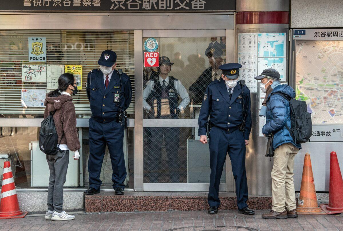 People wearing face masks ask directions from police officers who are also wearing face masks, at a police box by Shibuya crossing in Tokyo, Japan on Feb. 27, 2020. (Carl Court/Getty Images)