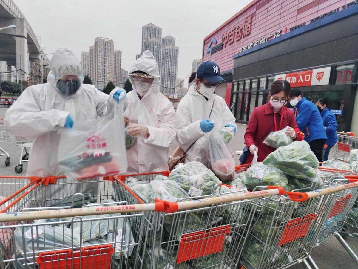 Community workers and volunteers wearing face masks sort and pack groceries from a supermarket purchased through group orders after supermarkets stopped selling to individuals, in Wuhan, the epicenter of the novel coronavirus outbreak, in Hubei Province, China, on Feb. 24, 2020. (China Daily via Reuters)