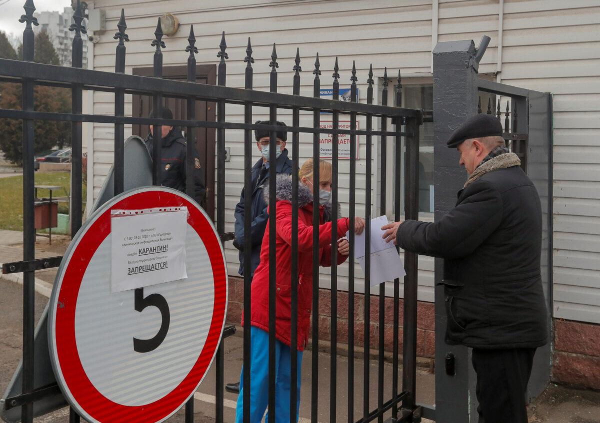 A visitor interacts with a staff member at a gate of a hospital for infectious diseases, after Belarus registered the first case of coronavirus infection in the country, in Minsk, Belarus on Feb. 28, 2020. (Vasily Fedosenko/Reuters)
