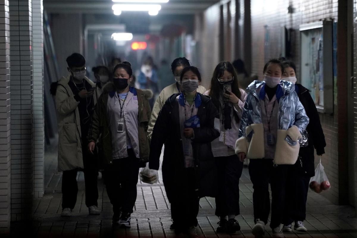 Workers wearing masks walk outside their dormitory in an electronics manufacturing factory in Shanghai on Feb. 12, 2020. (Aly Song/Reuters)