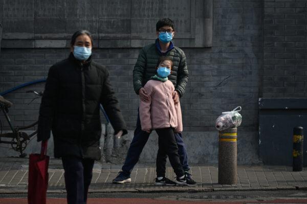 A man and a girl wearing face masks wait to cross a street in Beijing on Feb. 28, 2020. (STR/AFP via Getty Images)