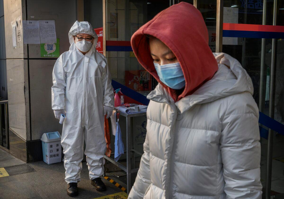 A Chinese worker wears a protective suit and mask as he waits to check the temperature of customers entering a grocery store in Beijing, China on Feb. 28, 2020. (Kevin Frayer/Getty Images)
