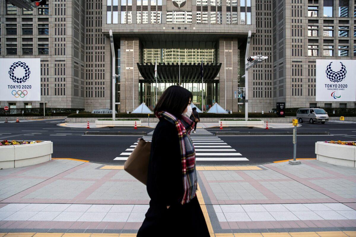 A woman wearing a protective face mask, following an outbreak of the coronavirus, walks past banners of the upcoming Tokyo 2020 Olympic and Paralympic Games outside the Tokyo Metropolitan Government building in Tokyo, Japan on Feb. 28, 2020. (Athit Perawongmetha/Reuters)