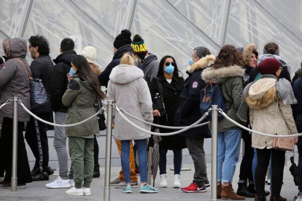 Tourists, some wearing a mask, queue to enter the Louvre museum Friday, in Paris, on Feb. 28, 2020. (Rafael Yaghobzadeh/AP)