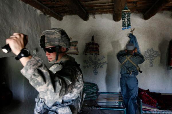 U.S. First Lt. Shane Oravsky (L) of the 101st Airborne Division searches a house with an Afghan police officer in Mandozai, in Khost province, Afghanistan, on April 18, 2008. (Rafiq Maqbool/AP)